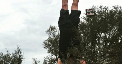 man doing handstand near bushes