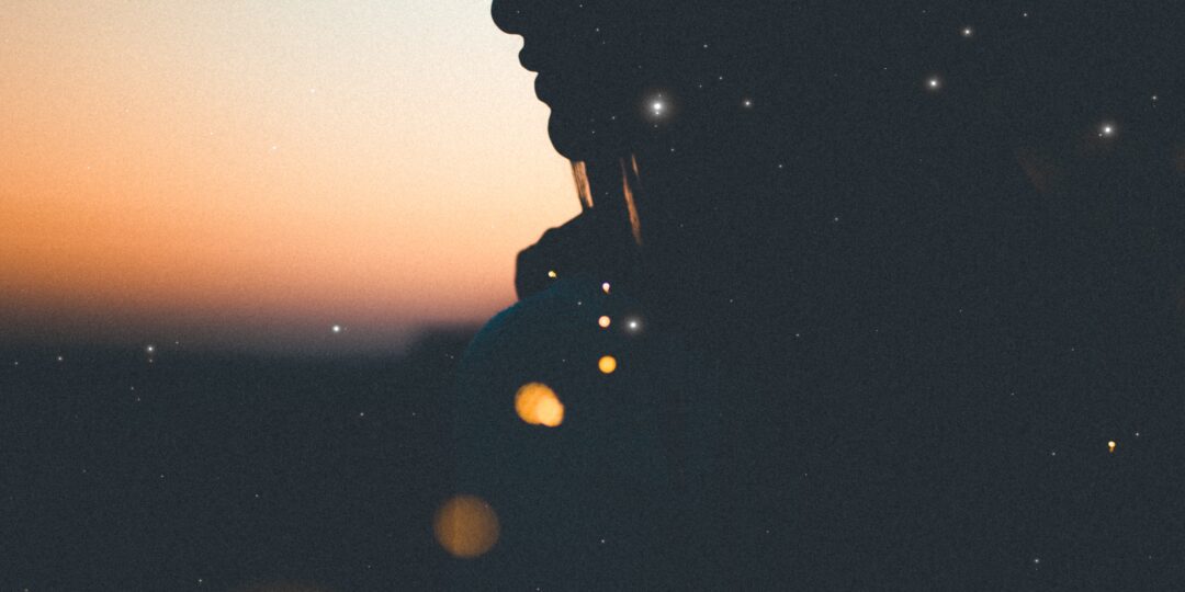 female silhouette with crescent moon in background at dusk