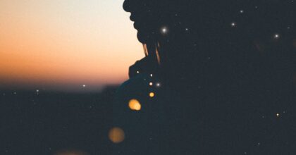 female silhouette with crescent moon in background at dusk