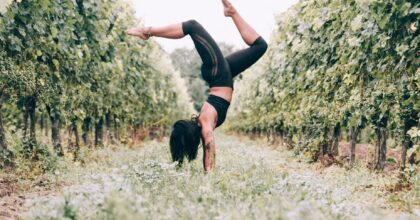yoga practicing woman doing a handstand in an orchard