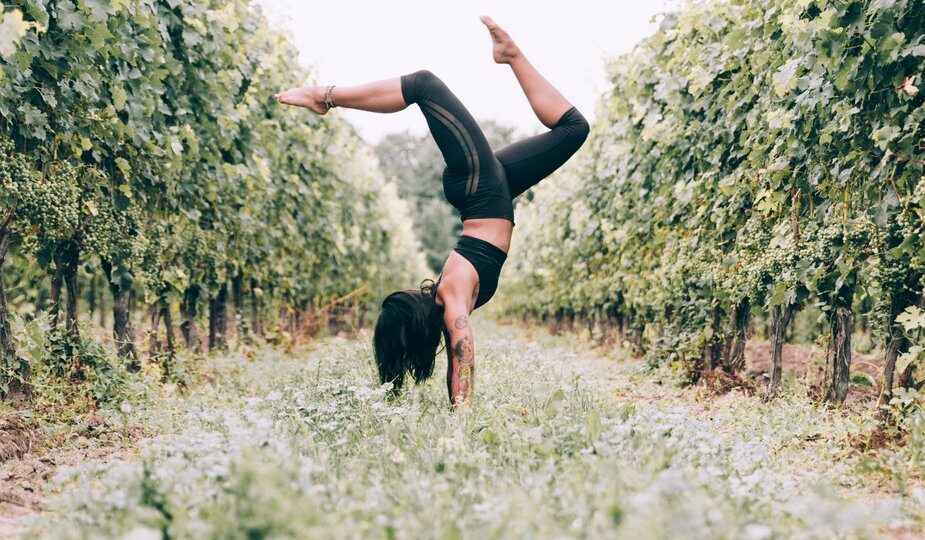 yoga practicing woman doing a handstand in an orchard