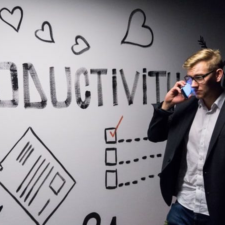 man on cell phone walking by a wall with the word productivity on it