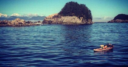 Childs post on standup paddle board on a lake with island in background
