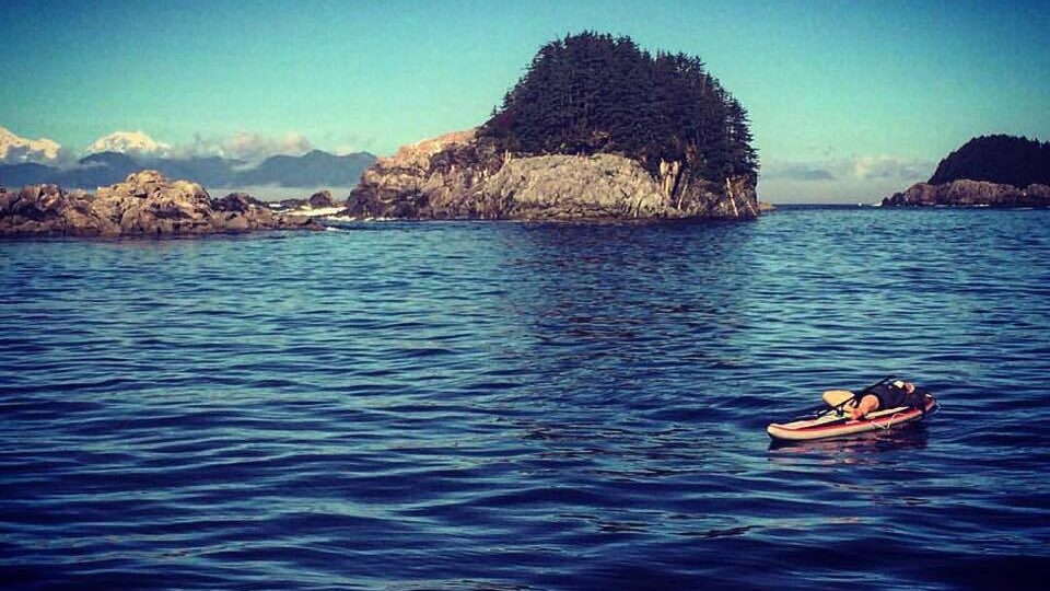 Childs post on standup paddle board on a lake with island in background